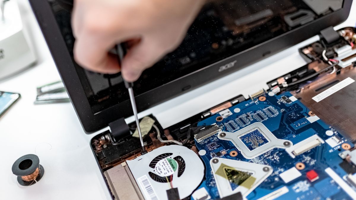 Detail van een geopende laptop waarbij een onderdeel met gereedschap wordt nagekeken