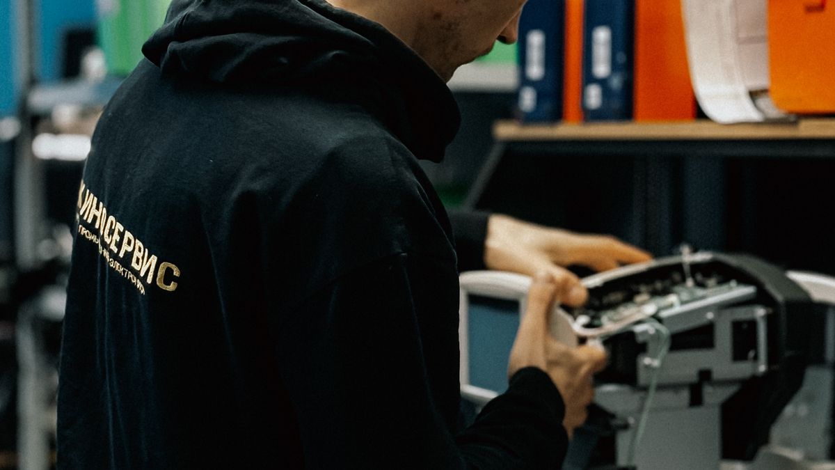Technicus die in een werkplaats een kantoorprinter onderzoekt en onderhoud uitvoert